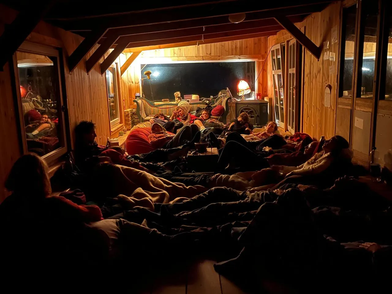 Viele Menschen liegen auf dem Boden und kuscheln in einem kleinen Gemeinschaftsraum